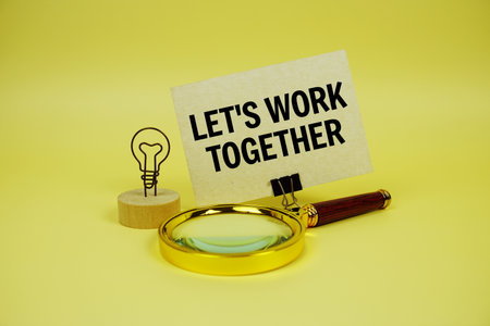 Let's Work Together text message on paper card with magnifying glass on yellow backgroundの写真素材