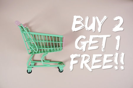 Buy 2 Get 1 Free!! Special Offer Promotion and trolley shopping cart on pink backgroundの写真素材