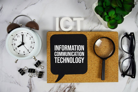 ICT - Information Communication Technology acronym with alarm clock and magnifying glass, business concept backgroundの写真素材