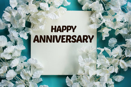 Happy Anniversary text with flowers frame decoration top view on blue backgroundの写真素材