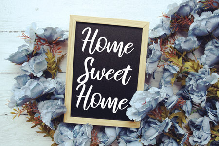 Home Sweet Home text with flowers frame decoration top view on wooden background