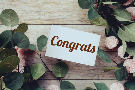 Congrats text message with flower decoration on wooden background