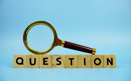 Question with wooden blocks alphabet letters and Magnifying glass on blue backgroundの写真素材