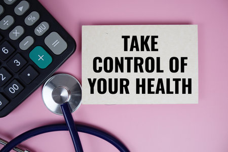 Take control of your Health text with calculator and stethoscope on pink backgroundの写真素材
