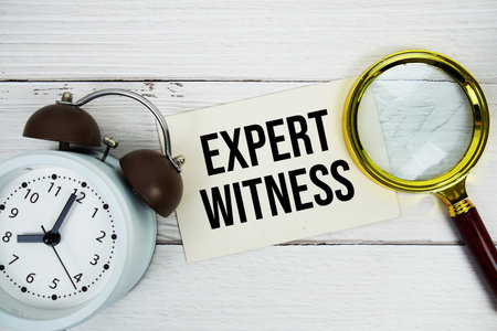 Expert Witness text message on sticky note with magnifying glass and alarm clock on woodenの写真素材