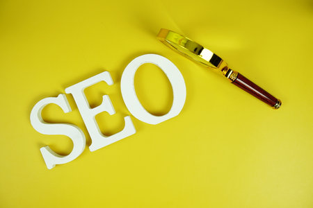 SEO Abbreviation of Search Engine Optimization alphabet letters with magnifying glass on yellow backgroundの写真素材