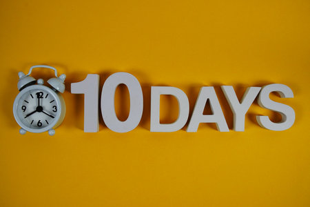 10 Days alphabet letters with alarm clock on yellow backgroundの写真素材