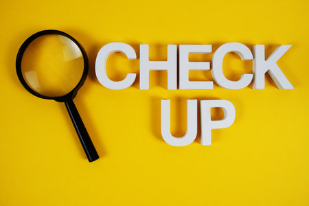 Check up text message and magnifying glass on yellow backgroundの写真素材