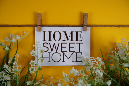 Home Sweet Home text on paper card with flower blooming decoration on yellow backgroundの写真素材