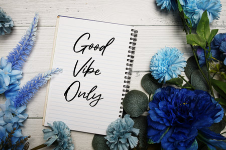 Good Vibe Only text with blue flowers bouquet decoration on wooden background