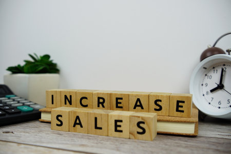 Alarm clock with wooden blocks alphabet letters INCREASE SALES text message on wooden backgroundの写真素材