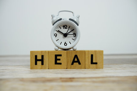 Time to Heal with wooden blocks alphabet letters and alarm clock on wooden backgroundの写真素材