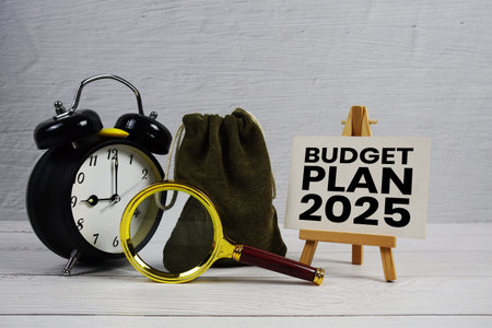 Budget Plan 2025 text with alarm clock and magnifying glass on wooden background