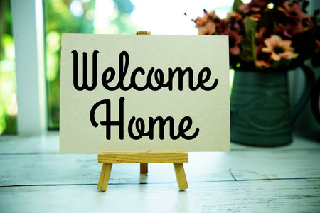 Welcome Home text on paper card with easel on wooden backgroundの写真素材