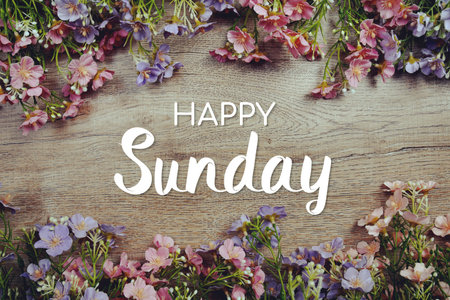 Happy Sunday text message with flowers decoration on wooden backgroundの写真素材