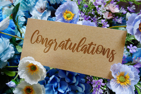 Congratulations text write on paper card with flowers decoration on wooden backgroundの写真素材