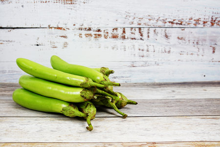 Fresh green long Thai eggplants on wooden backgroundの写真素材