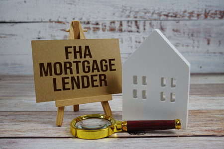 FHA Mortgage Lender on paper card with magnifying glass and white house model on wooden backgroundの写真素材