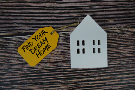 Find Your Dream Home text on price tag with white house model flat lay on wooden backgroundの写真素材