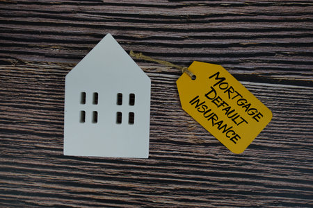 Mortgage Default Insurance text on price tag with white house model flat lay on wooden background