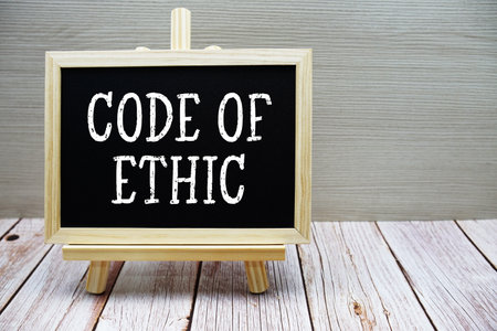 Code Of Ethic text written on chalkboard with easel on wooden backgroundの写真素材