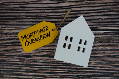 Mortgage Overview text on price tag with white house model flat lay on wooden background