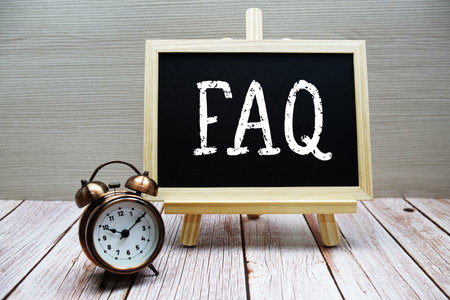 FAQ text written on chalkboard with alarm clock on wooden backgroundの写真素材