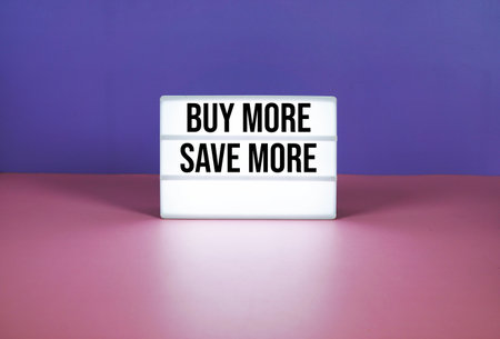 Buy More Save More text on LED lightbox on purple and pink geometric backgroundの写真素材