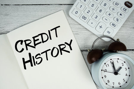 Credit History text on paper notebook page with alarm clock and calculator on wooden backgroundの写真素材