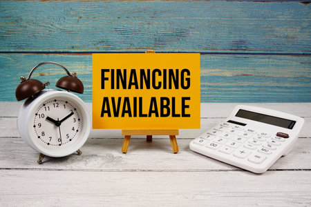 Financing Available text written on paper card with calculator and alarm clock on wooden backgroundの写真素材