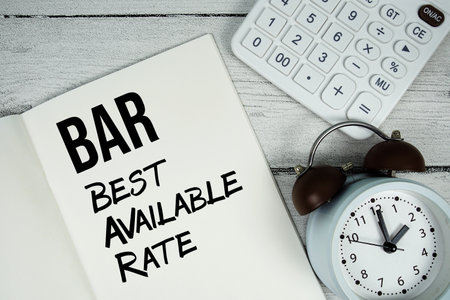 BAR Best Available Rate text on paper notebook page with alarm clock and calculator on wooden backgroundの写真素材