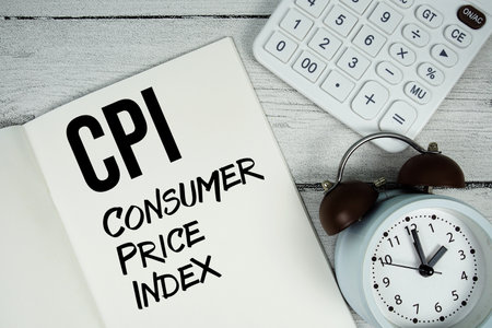 CPI Consumer Price Index text on paper notebook page with alarm clock and calculator on wooden backgroundの写真素材