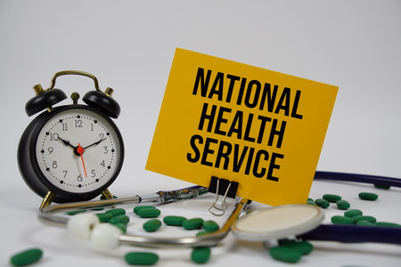National Health Service text with alarm clock and Stethoscope on white backgroundの写真素材