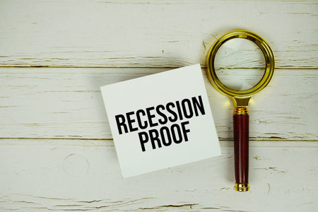 Recession Proof text message on sticky note with magnifying glass on wooden backgroundの写真素材