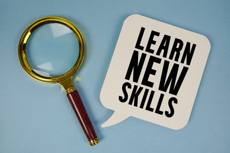 Learn New Skills text with magnifying glass on blue backgroundの写真素材