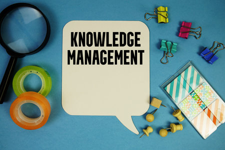 Knowledge Management text with magnifying glass on blue background