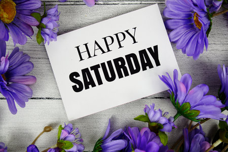 Happy Saturday text with flower decoration on wooden backgroundの写真素材