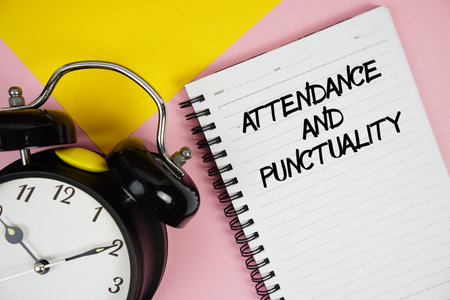 Attendance And Punctuality text written on notepad with alarm clock on pink backgroundの写真素材