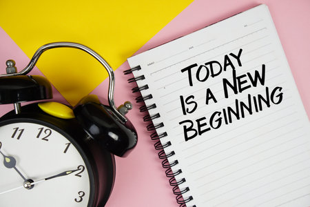 Today Is A New Beginning text written on notepad with alarm clock on pink backgroundの写真素材