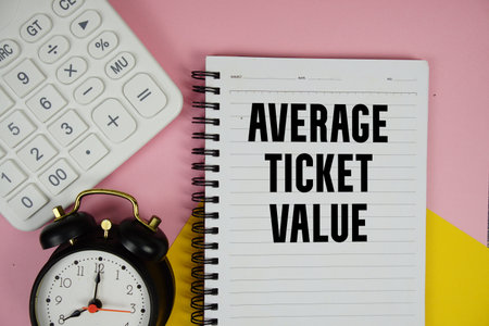 Average Ticket Value text written on notepad with calculator and alarm clock on pink backgroundの写真素材
