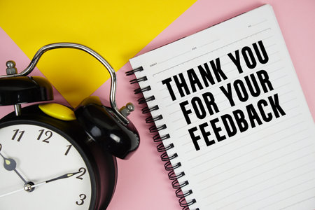 Thank you for your Feedback text written on notepad with alarm clock on pink backgroundの写真素材