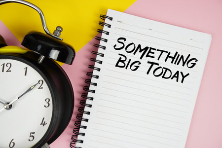 Something Big Today text written on notepad with alarm clock on pink backgroundの写真素材