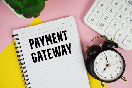 Payment Gateway text written on notepad with calculator and alarm clock on pink backgroundの写真素材