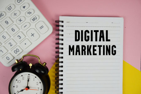 Digital Marketing text written on notepad with calculator and alarm clock on pink backgroundの写真素材