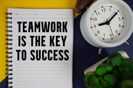 Teamwork is the Key to Success text written on notepad with alarm clock on yellow and navy blue backgroundの写真素材