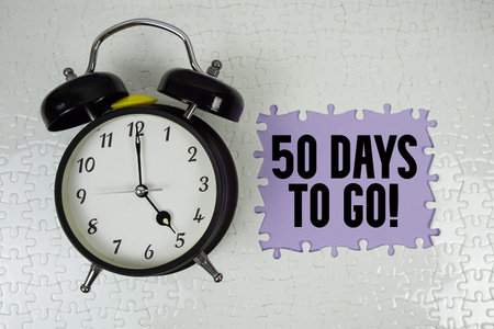 50 Days To Go! text with alarm clock on purple background