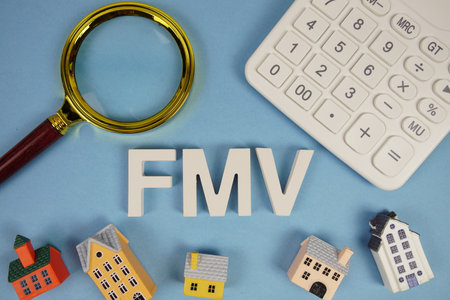 FMV abbreviation of Fair Market Value alphabet letters with house model, magnifying glass and calculator on blue backgroundの写真素材