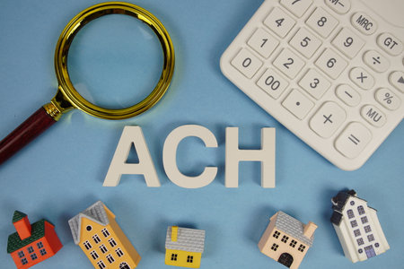 ACH abbreviation of Automated Clearing House alphabet letters with house model, magnifying glass and calculator on blue backgroundの写真素材