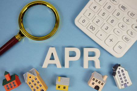 APR abbreviation of Annual Percentage Rate alphabet letters with house model, magnifying glass and calculator on blue backgroundの写真素材