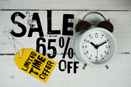 Sale 65% off Limited Time Offer text with alarm clock on wooden backgroundの写真素材